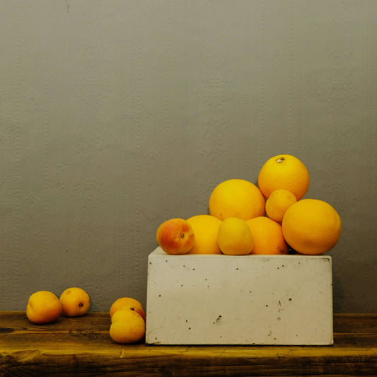 Orangen und Aprokosen in der Beton Schale BLOCK. Das Foto sieht aus wie ein gemaltes Stillleben