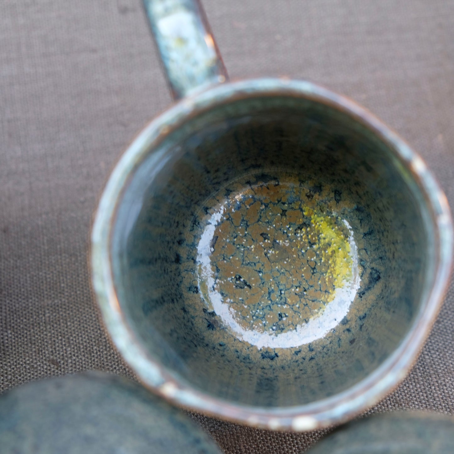 Detailaufnahme der Steingut Tasse Krumme Lanke in der Farbe Petrol. Die Detailaufnahme zeigt sehr schön die Muster und Farbe der reaktiven Glasur 