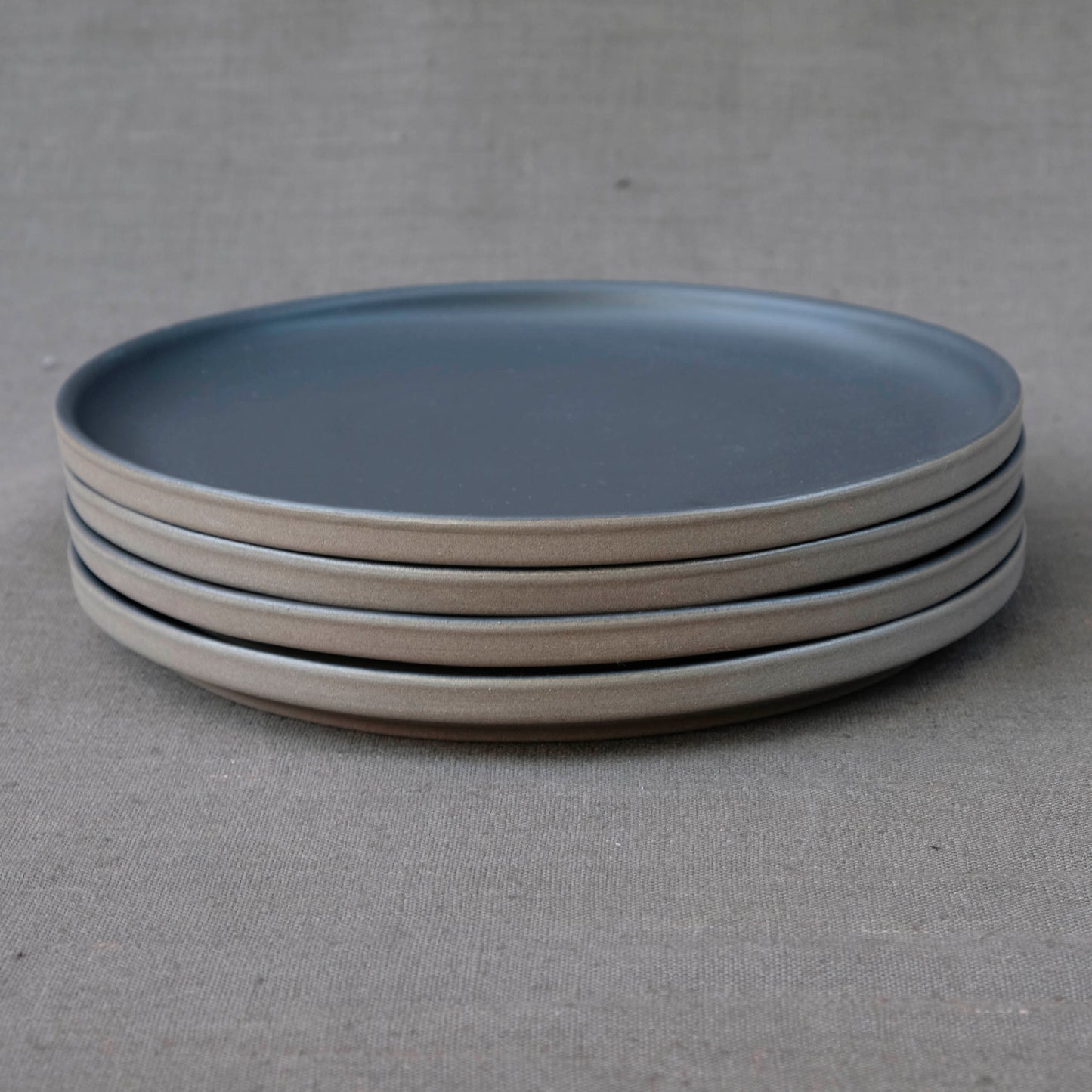 Set aus 4 grossen Steinzeug Tellern der Kollektion Lietzensee. Die Dinnerteller sind in schwarz mit unglasiertem Rand, was ihnen einen industrial Design Charme gibt